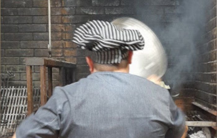 Cuiner atançant la carn a la brasa del Restaurant Caliu