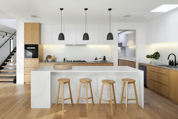 Cocina blanca con taburetes de madera y lámparas colgantes