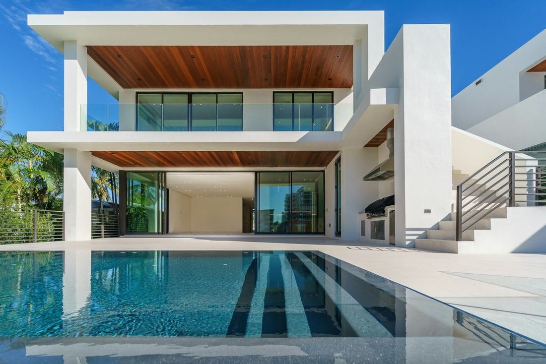 Villa moderna con techo de madera y piscina iluminada al anochecer